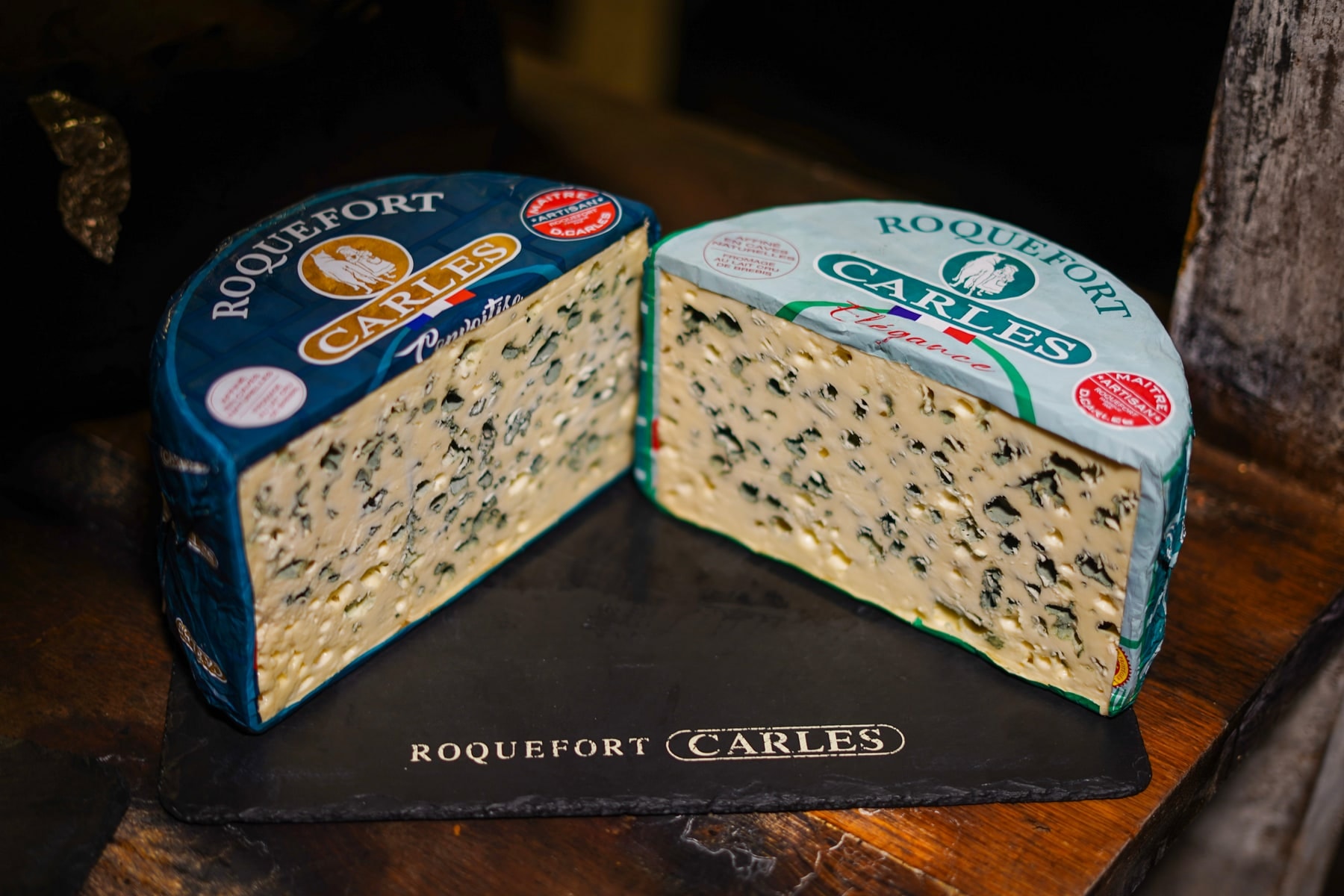 Roquefort Carles Convoitise et Roquefort Carles Élégance, coupés face à face, posés sur une ardoise gravée « Roquefort Carles »